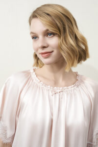 Close-up of female model wearing pink MANITO Luella Lace Silk Short Sleeve Dress, focusing on the gathered neckline.