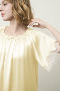 Side view of female model wearing the yellow MANITO Luella Lace Silk Short Sleeve Dress, highlighting the lace-trimmed sleeves.