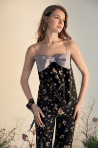 Woman in Lrisette Bow Camisole and Silk Pants Set featuring a floral pattern and a delicate bow on the neckline.