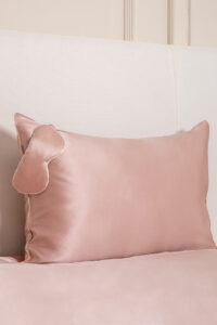 HA Silk Pillowcase & Eye Mask Gift Box in blush pink, featuring a silk pillowcase and matching eye mask on a bed.
