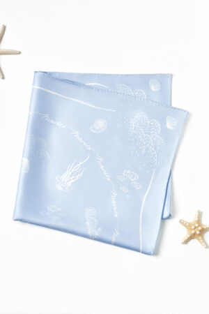 Folded MANITO Ocean Blue Silk Scarf showing underwater creatures and wave elements on glossy mulberry silk.