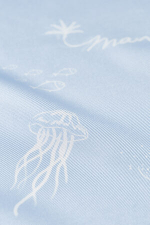 Macro view of jellyfish print and palm illustration on the smooth surface of the MANITO Ocean Blue Silk Scarf.