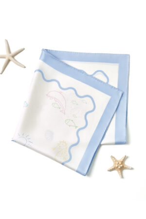 Folded MANITO Ocean Wave Silk Scarf with pastel sea motifs and soft blue border, styled with starfish decor.