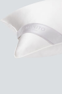 Luxurious white silk pillow with elegant 'MANITO Silk Moments' tag detail for a refined bedroom setting.