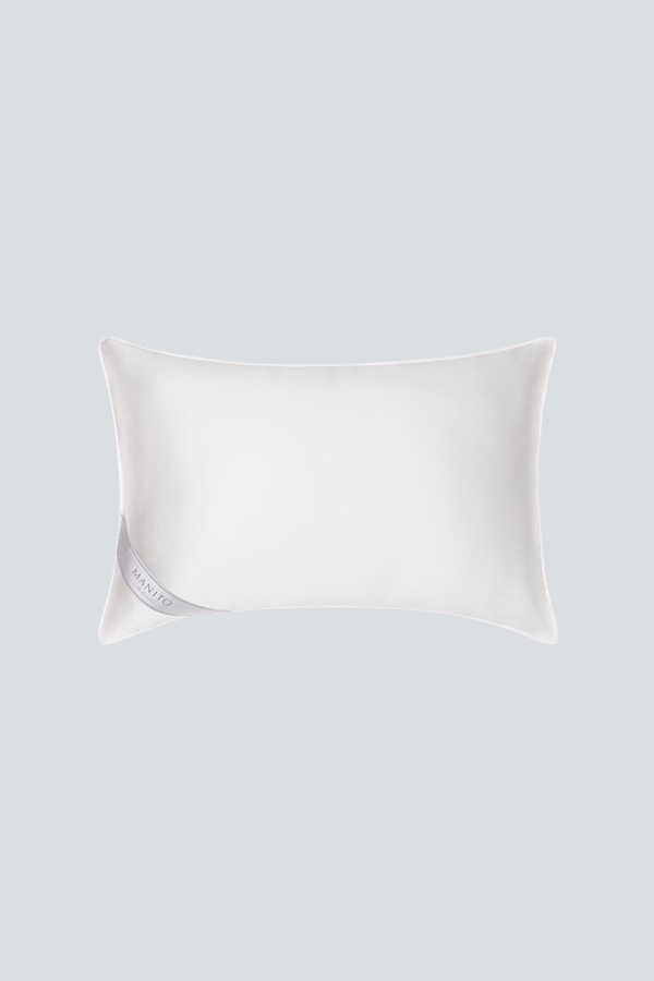 Premium silk filled pillow with 'MANITO' tag, offering a soft and luxurious addition to bedroom comfort.