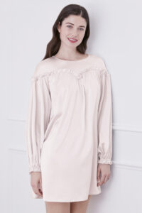 Elegant woman smiling in ballet pink silk mini dress, showcasing the unique design.