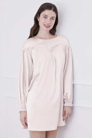 Elegant woman smiling in ballet pink silk mini dress, showcasing the unique design.