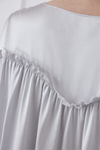 Close-up of back embroidery detail on Sophia silk mini dress, featuring "MANITO Silk Moment" embroidery.