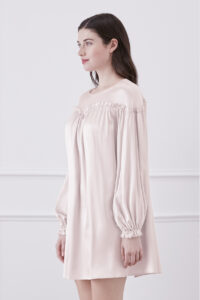 Side view of woman in ballet pink silk mini dress showcasing unique ruffle trim and lantern sleeves design.