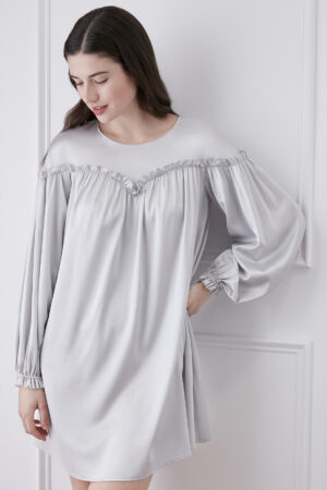 a woman in silver gray silk mini dress with lantern sleeves and heart-shaped ruffle collar detail.