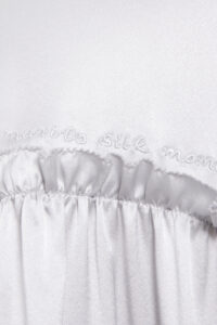 Close-up detail of "MANITO Silk Moment" embroidery on Sophia silk mini dress, showcasing fine craftsmanship.