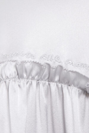 Close-up detail of "MANITO Silk Moment" embroidery on Sophia silk mini dress, showcasing fine craftsmanship.
