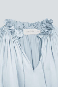 Front view of baby blue silk dress showcasing ruffle trim collar and MANITO label, with glossy silk texture.