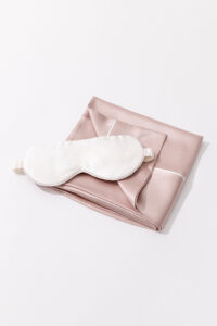 Sweet Dreams Silk Pillowcase & Eye Mask Set featuring a white silk eye mask placed on a pink silk pillowcase.