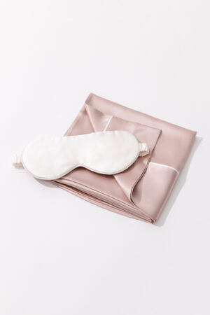 Sweet Dreams Silk Pillowcase & Eye Mask Set featuring a white silk eye mask placed on a pink silk pillowcase.