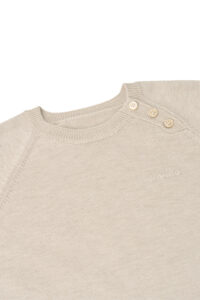 Close-up of Mellow Baby's knit onesie shoulder, highlighting the ribbed neckline and small side buttons.