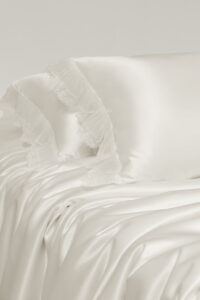 Side view of Moonlight silk bedding, revealing flowing silk folds and soft lace edges.