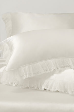 Stacked pillowcases from Moonlight silk collection showcase smooth silk texture and refined lace ruffles for a romantic look.
