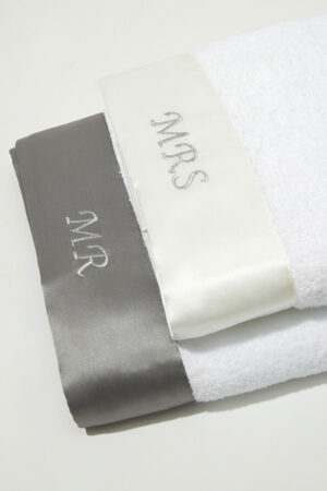 Mr. & Mrs. Bath Towel set flat lay with matching gray and white silk trims, symbolizing love and harmony in daily life.