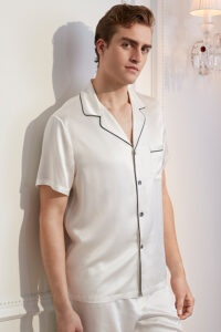 Man in stylish white Men's Short Sleeve Silk Pajama Set with contrasting black piping detail.