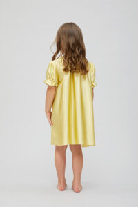 Back view of the child in a yellow shirley silk nightgown with wavy hair.