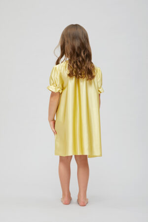 Back view of the child in a yellow shirley silk nightgown with wavy hair.