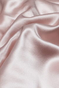 Close-up of a soft pink silk fabric from a 5-piece bedding set for babies.