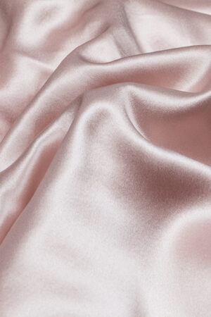 Close-up of a soft pink silk fabric from a 5-piece bedding set for babies.