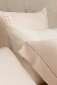 A detailed close-up of delicate water-soluble lace trim with the hollowed-out MANITO logo on New Aqua Bedding Sets.