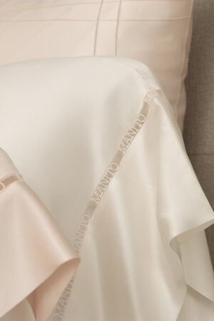 An up-close shot of the minimalistic MANITO logo hollow lace, intricately woven with yarn on MANITO New Aqua Bedding Sets.