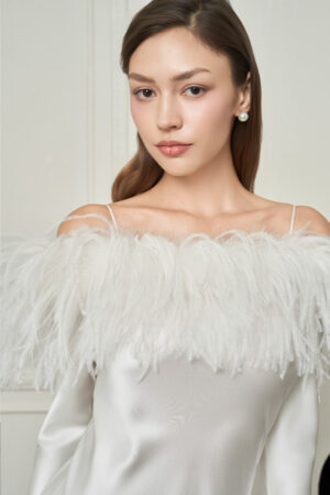 Close-up of woman in white New Diva Feather Off-the-shoulder Dress, soft feathers brushing her shoulders for a dreamy mood.