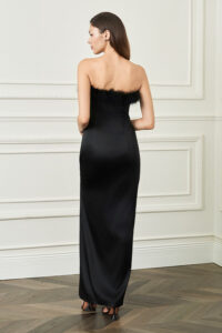 Back view of woman in black New Diva feather strapless dress, smooth satin column creating a clean, elongated silhouette.