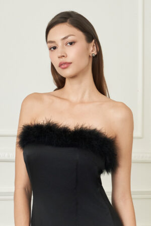 Close-up of woman in black New Diva feather strapless dress, soft ostrich feathers framing the neckline for refined evening glamour.