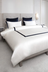 MANITO French bedding set with white silk duvet cover and navy trim, creating an elegant and refined bedroom aesthetic.