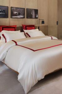 Classic MANITO French bedding set with white silk duvet cover and bold red trim, adding a touch of luxury to the bedroom decor.