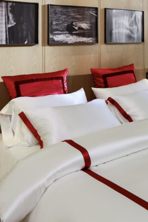Detailed view of MANITO white silk duvet cover with deep red trim, showcasing the fine design.