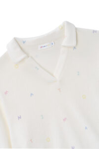 Close-up of New Signature Children's Knit Pajama top, showing the soft collar and playful letter patterns on white knit.