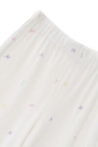New Signature Children's Knit Pajama pants, highlighting the elastic waistband and all-over rainbow lettering on the plush white fabric.