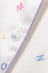 Detail shot of New Signature Kid's Pajama Set button and letter print with smooth silk texture.