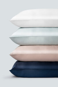 Stack of premium silk pillowcases in assorted colors including white, sky blue, soft pink, and navy, representing the varied collection from MANITO.