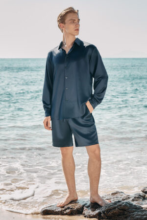 Full-length front view of model in MANITO Ocean Blue Dolphin Men's Pajama Set by the sea.