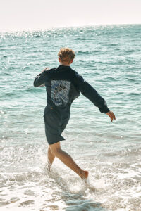 Action shot of model running into ocean in MANITO Ocean Blue Dolphin Men's Pajama Set.