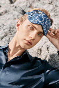 Close-up of the MANITO Ocean Blue Dolphin Silk Eye Mask worn by a model, highlighting the dolphin print and silk texture.