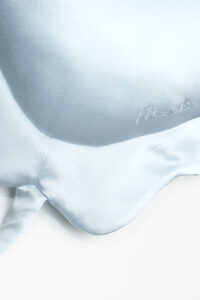 Close-up of MANITO whale-shaped pillow's embroidered eye and fin details, emphasizing craftsmanship.