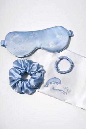 Flat lay of MANITO Ocean Blue Sleeping Beauty Gift Box contents: eye mask, two scrunchies, and pillowcase.