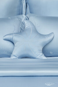 MANITO Ocean Starfish Throw Pillow on ocean blue bedding with embroidered marine motifs.