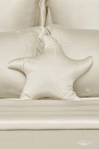 MANITO Ocean Starfish Throw Pillow on cream silk bedding set with subtle ocean-themed design.