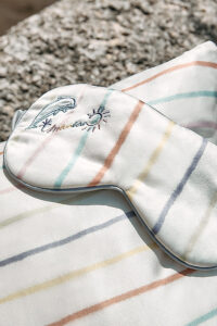 A luxurious MANITO silk eye mask with rainbow stripes and delicate embroidery.