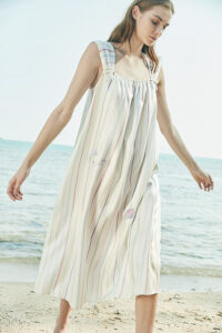 A model wearing MANITO rainbow stripe dress, flowing elegantly by the beach.