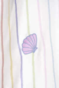 Close-up of the embroidered seashell detail on MANITO rainbow stripe dress, adding a touch of elegance to the silky fabric.